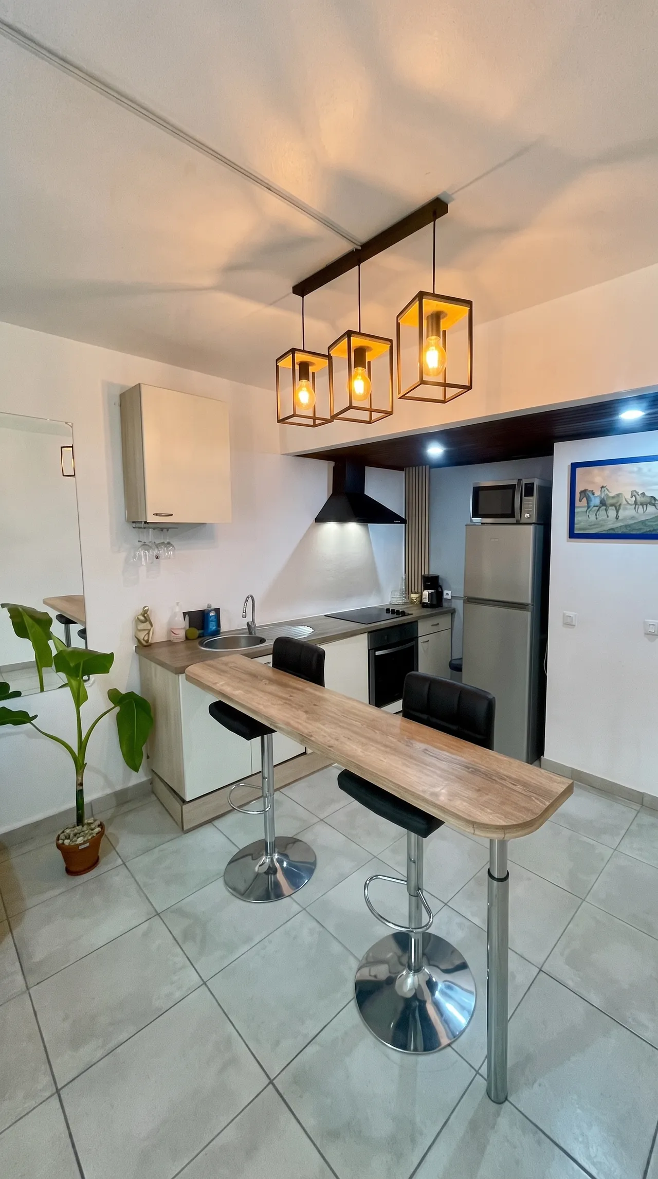 Cuisine avec table de bar, frigo, micro-onde, plaque de cuisson, évier