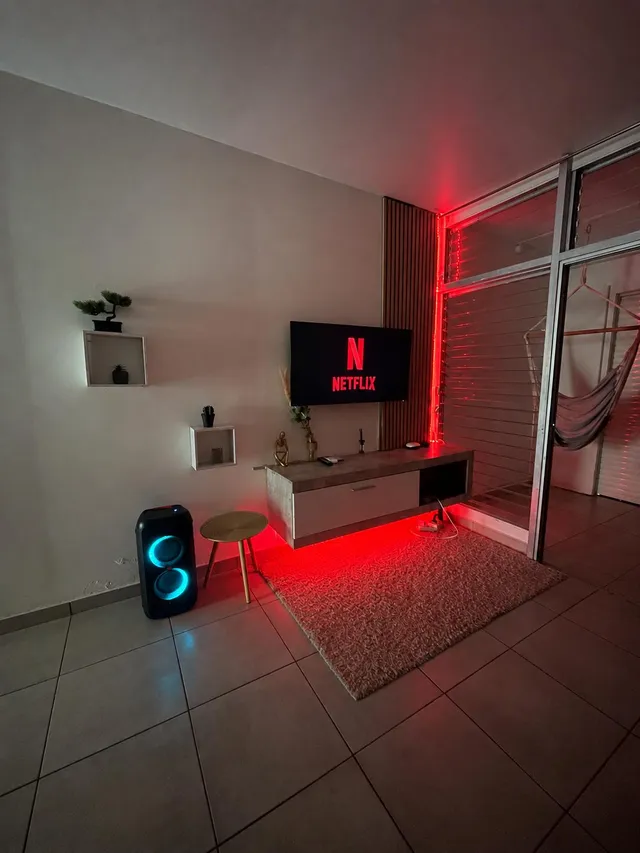 Salon où est visible une Télé avec un meuble TV lumineux en rouge.